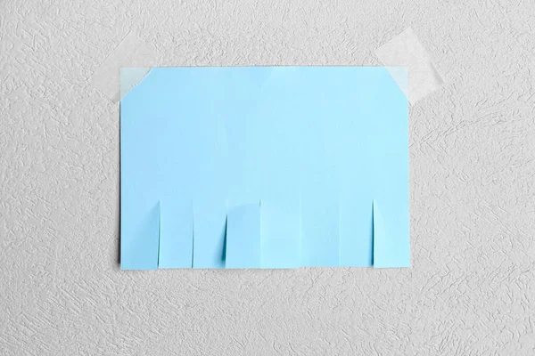 Blank paper tear-off ad on light wall