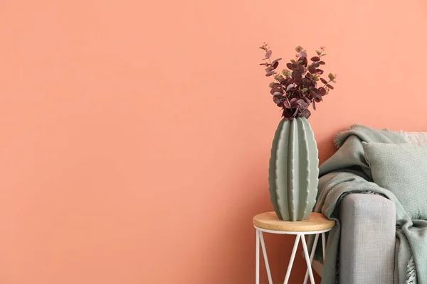 ピンクの壁の近くのテーブルとグレーのソファの上にユーカリと花瓶 — ストック写真