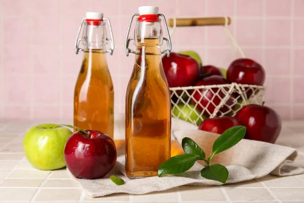 Glasflaschen Mit Frischem Apfelessig Und Obstkorb Auf Rosa Fliesen — Stockfoto