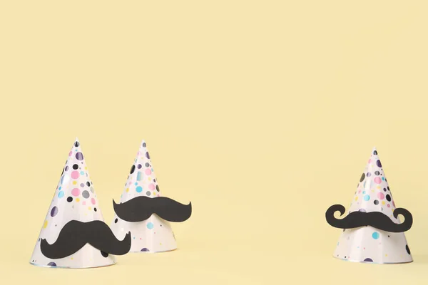 Party hats with paper mustaches on color background