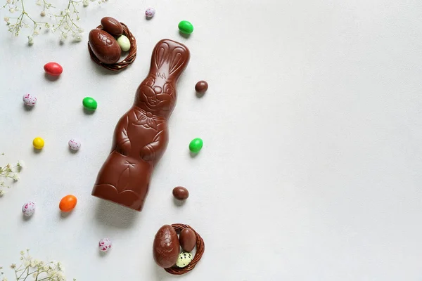 白い背景に卵と花を持つチョコレートイースターバニー — ストック写真