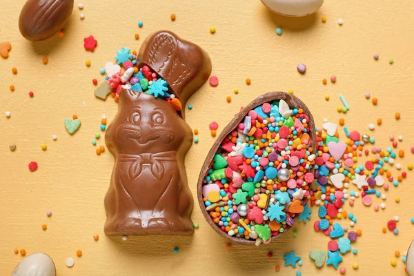 stock image Chocolate Easter bunny with eggs and sprinkles on yellow background