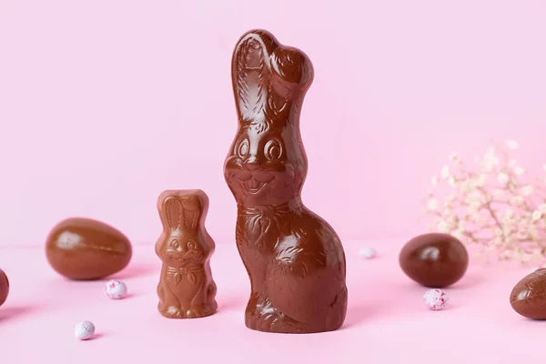 stock image Chocolate Easter bunny with eggs on pink background, closeup