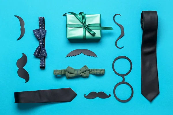Composition with paper decor, ties and gift for Father\'s Day celebration on color background
