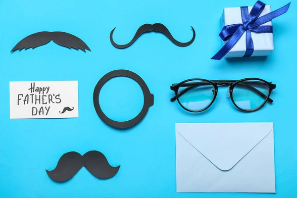 Composition with paper decor, eyeglasses and gift for Father\'s Day celebration on color background