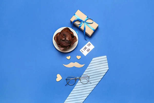 Composition with male accessories, muffin and gift for Father\'s Day celebration on blue background