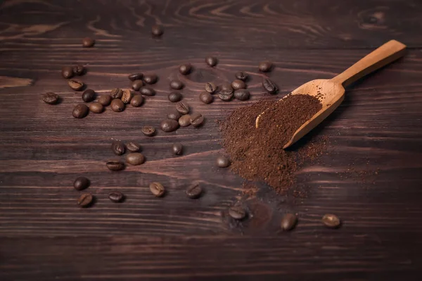 Scoop of coffee powder and beans on dark wooden background