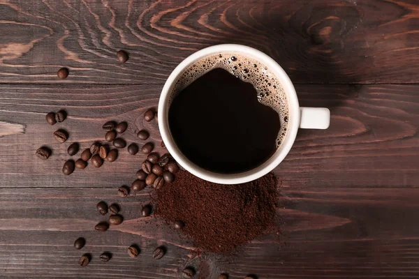濃い木目の背景に粉と豆のコーヒーカップ — ストック写真