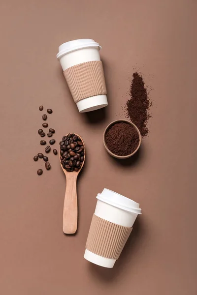 Cups with coffee powder and beans on brown background