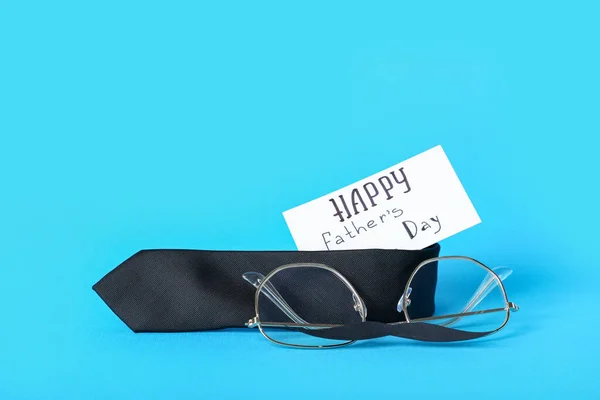 stock image Paper with text HAPPY FATHER'S DAY, necktie and eyeglasses on blue background