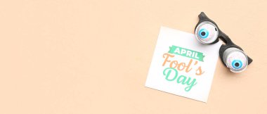 Kağıtlar APRIL FOOL 'un Günü ve bej arkaplan üzerinde komik gözlük ile metin için boşluk
