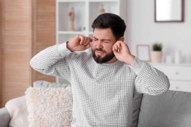 Evde gürültüden muzdarip öfkeli genç bir adam.