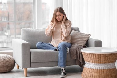 Evde gürültüden rahatsız olan genç bir kadın.