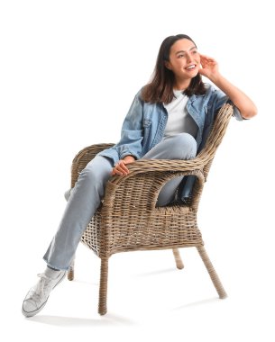 Young woman sitting in wicker armchair on white background