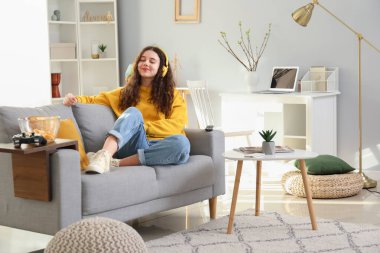 Evde müzik dinleyen kulaklıklı genç kız.