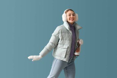 Pretty young woman with ice skates on blue background