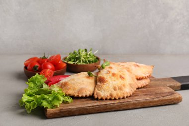 Ahşap tahta tahtada pişmiş et, marul, mikro yeşil ve arkaplanda sebzeler.