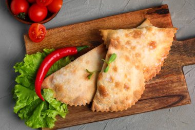 Ahşap tahta tahtada pişmiş et, marul ve sebzeler arkaplanda, yakın plan.