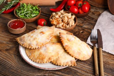 Ahşap zemin üzerinde pişmiş et, et, sebze, sos ve otlarla dolu tabaklar.