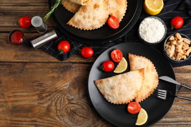 Ahşap zemin üzerinde fırında börek, et, un, sos ve domates tabakları.