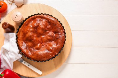 Beyaz ahşap masada, üzerinde pişirme şeklinde lezzetli etli turta olan bir tahta.