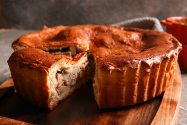 Gri grunge masasında lezzetli etli turta.