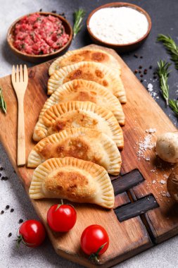 Lezzetli et börekleri ve siyah beyaz arka planda malzemeleri olan ahşap tahta pano, yakın plan.