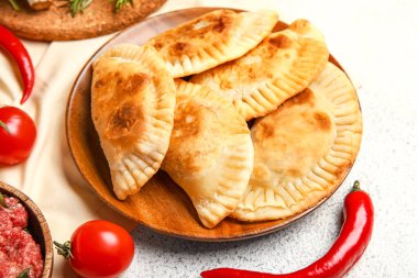 Tabakta lezzetli et börekleri ve sebzeler var, yakın plan.