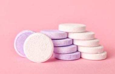 Pembe arka planda beyaz ve leylak çözünebilir tabletler