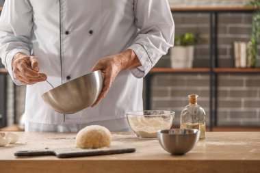 Erkek aşçı hamur işi yapıyor. Mutfaktaki masada, yakın plan.