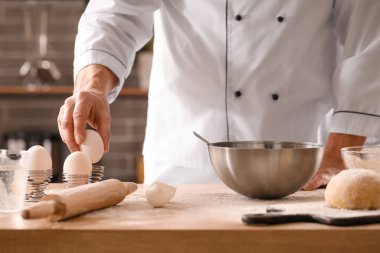 Erkek aşçı hamur işi yapıyor. Mutfaktaki masada, yakın plan.