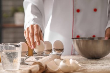 Mutfaktaki masada makarna için hamur yapan kadın aşçı, yakın plan.