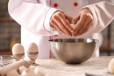 Mutfaktaki masada makarna için hamur yapan kadın aşçı, yakın plan.