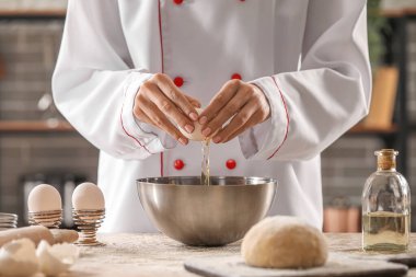Mutfaktaki masada makarna için hamur yapan kadın aşçı, yakın plan.