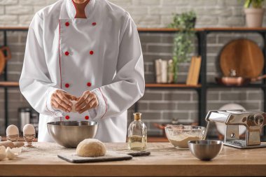 Mutfaktaki masada makarna için hamur yapan kadın aşçı, yakın plan.