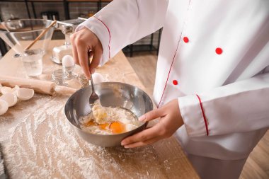 Mutfaktaki masada makarna için hamur yapan kadın aşçı, yakın plan.