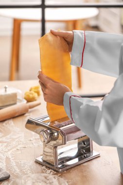 Mutfaktaki masada makineyle makarna yapan kadın aşçı, yakın plan.