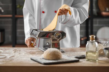 Mutfaktaki masada makineyle makarna yapan kadın aşçı, yakın plan.