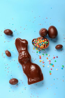 Çikolatalı Paskalya tavşanı, mavi arka planda yumurtalar ve serpiştirilmiş.