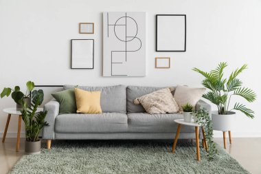 Oturma odasının içinde rahat bir kanepe, resimler ve ev bitkileri var.