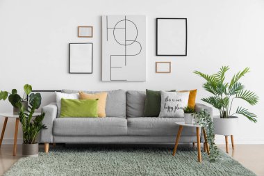 Oturma odasının içinde rahat bir kanepe, resimler ve ev bitkileri var.