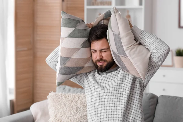 家で大きな音に悩まされている枕を持つ若い男 — ストック写真