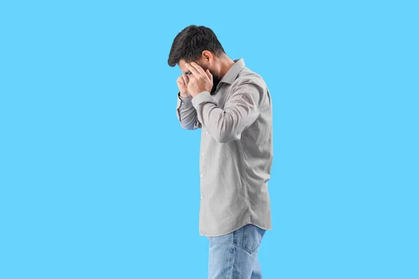 Young Man Suffering Loud Noise Blue Background — Stockfoto