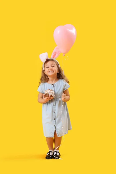 小兔子耳朵里的小女孩 戴着复活节蛋糕 黄色背景的气球 — 图库照片