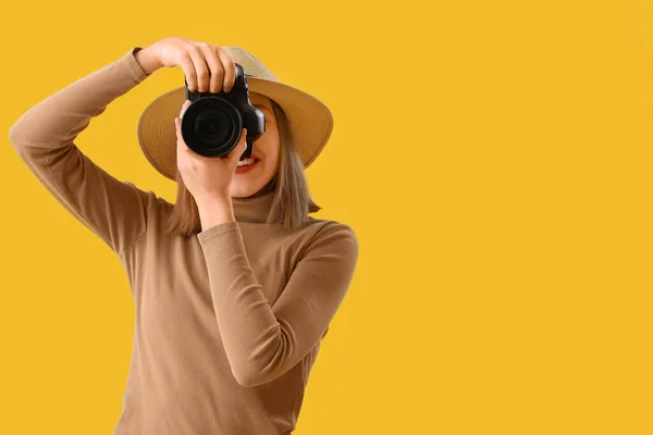 带黄色背景专业相机的女摄影师 — 图库照片