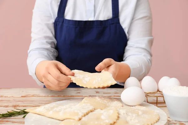 Woman with raw meat empanadas, flour and chicken eggs at light wooden table