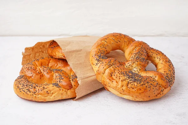 Paper bag with tasty pretzels on light background