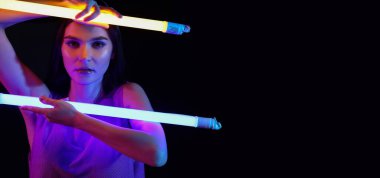 Koyu arkaplan üzerinde neon lambaları olan güzel bir kadının tonlu portresi.
