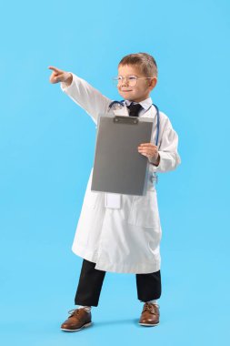 Mavi arka plandaki bir şeyi gösteren küçük sevimli bir doktor.