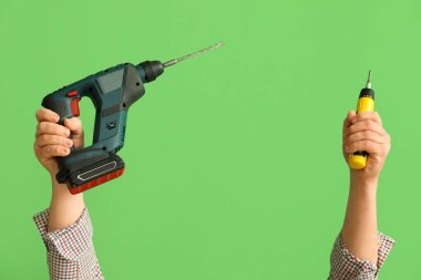 Yeşil arkaplanda matkap ve tornavida kullanan işçiler